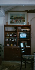 Black-and-white photo of a vintage wooden cabinet filled with antique books and collectibles.