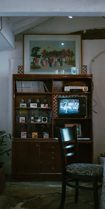 Black-and-white photo of a vintage wooden cabinet filled with antique books and collectibles.