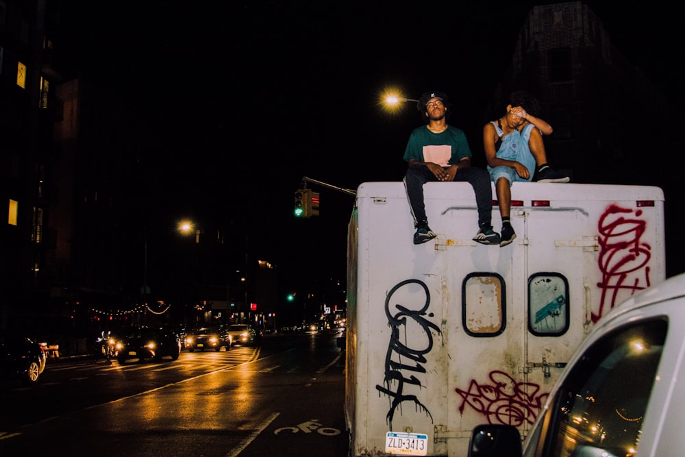 two man sitting on top of truck