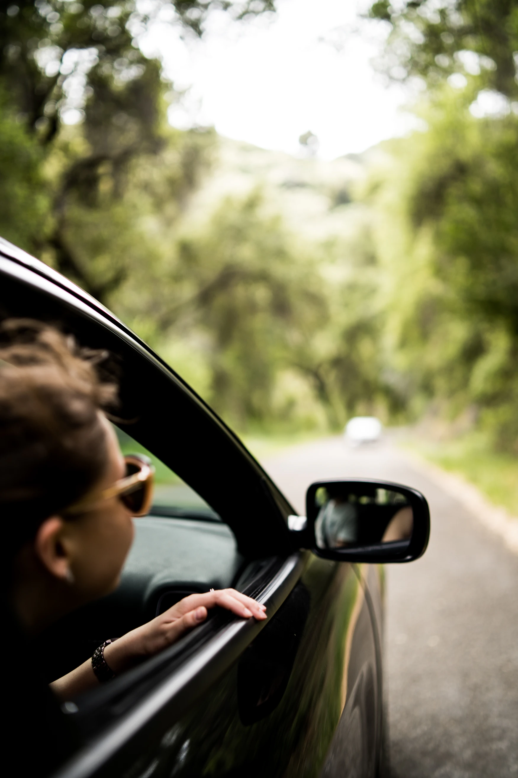 Passenger seated beside the window inside a car on a road trip