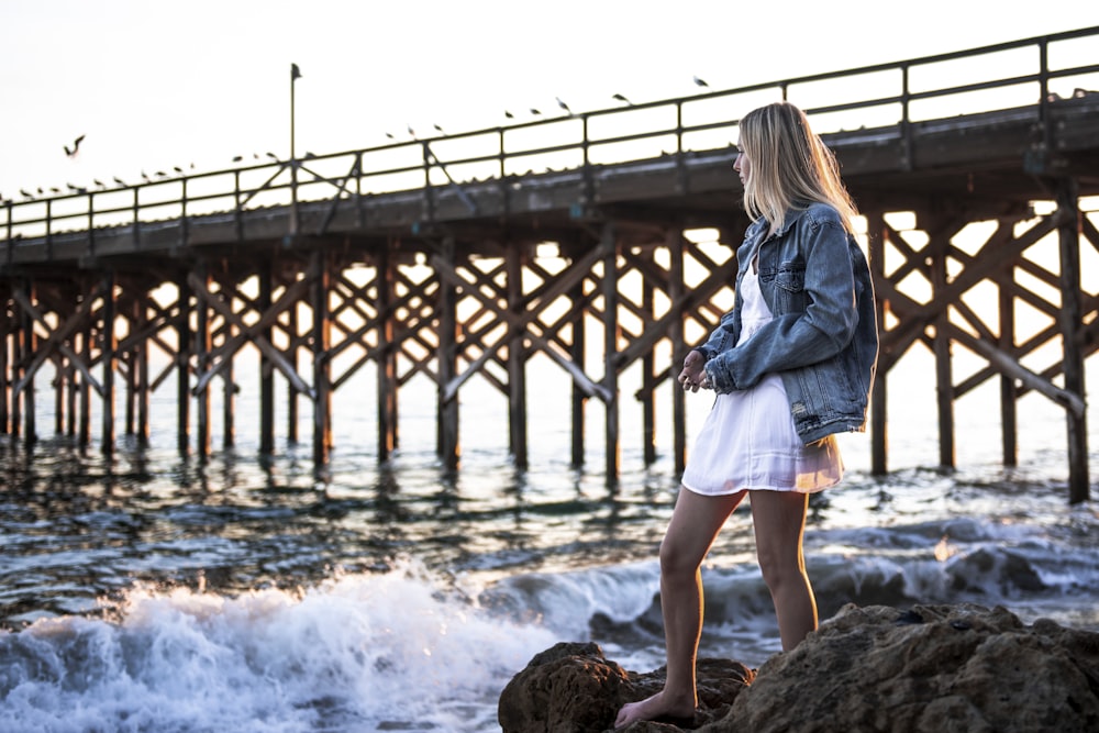 woman standing on seashore near bridge