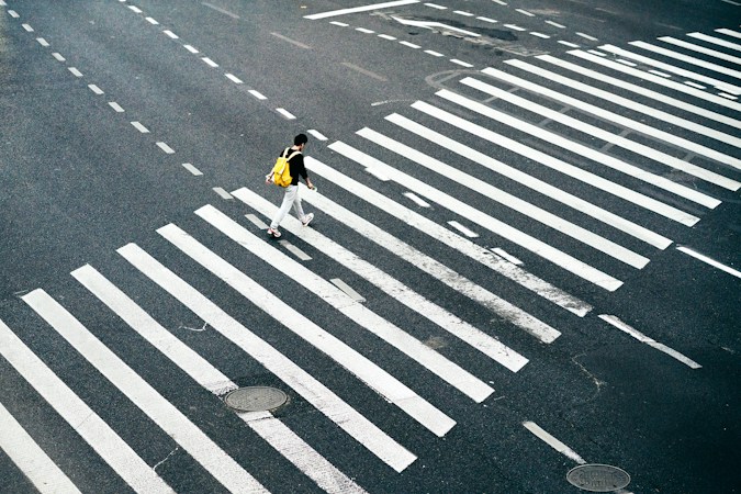 A person crossing a marked pedestrian lane on a quiet street during daylight