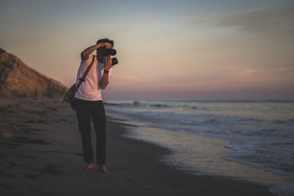 man taking photo of seashore