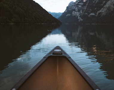 canoe on body of water with mountain background