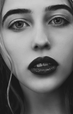 Black-and-white close-up of a model's face, highlighting striking features and intense expression.
