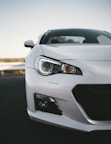white coupe parked near road barrier