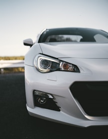 white coupe parked near road barrier