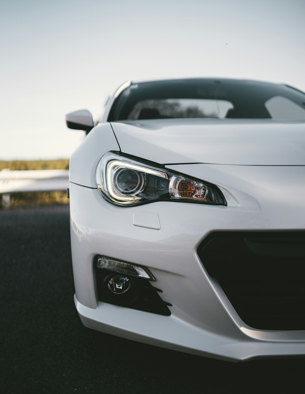 white coupe parked near road barrier