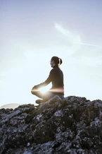 A peaceful scene of a person meditating outdoors at sunrise, embodying calm and focus.