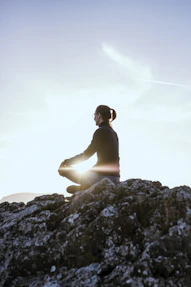 A serene scene of a man meditating outdoors at sunrise.