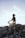 A person is sitting on a rocky surface outdoors, practicing meditation with sunlight shining through their arms. The sky is clear and the sun is low, creating a serene and peaceful atmosphere.