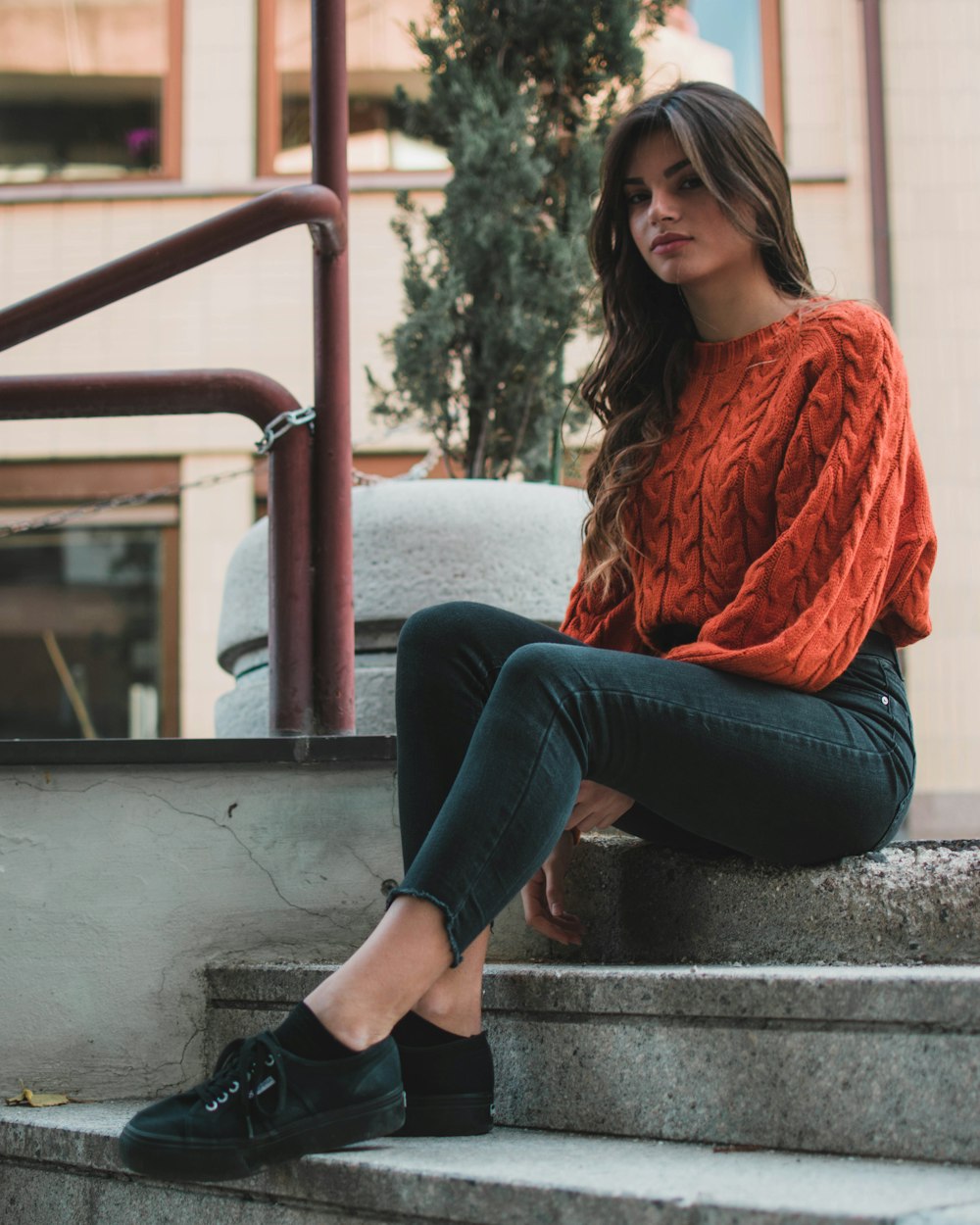 donna che indossa un maglione girocollo arancione seduto sulla scala