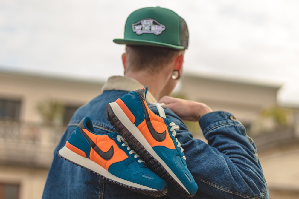 man holding pair of blue-white-and-orange Nike low-top shoes