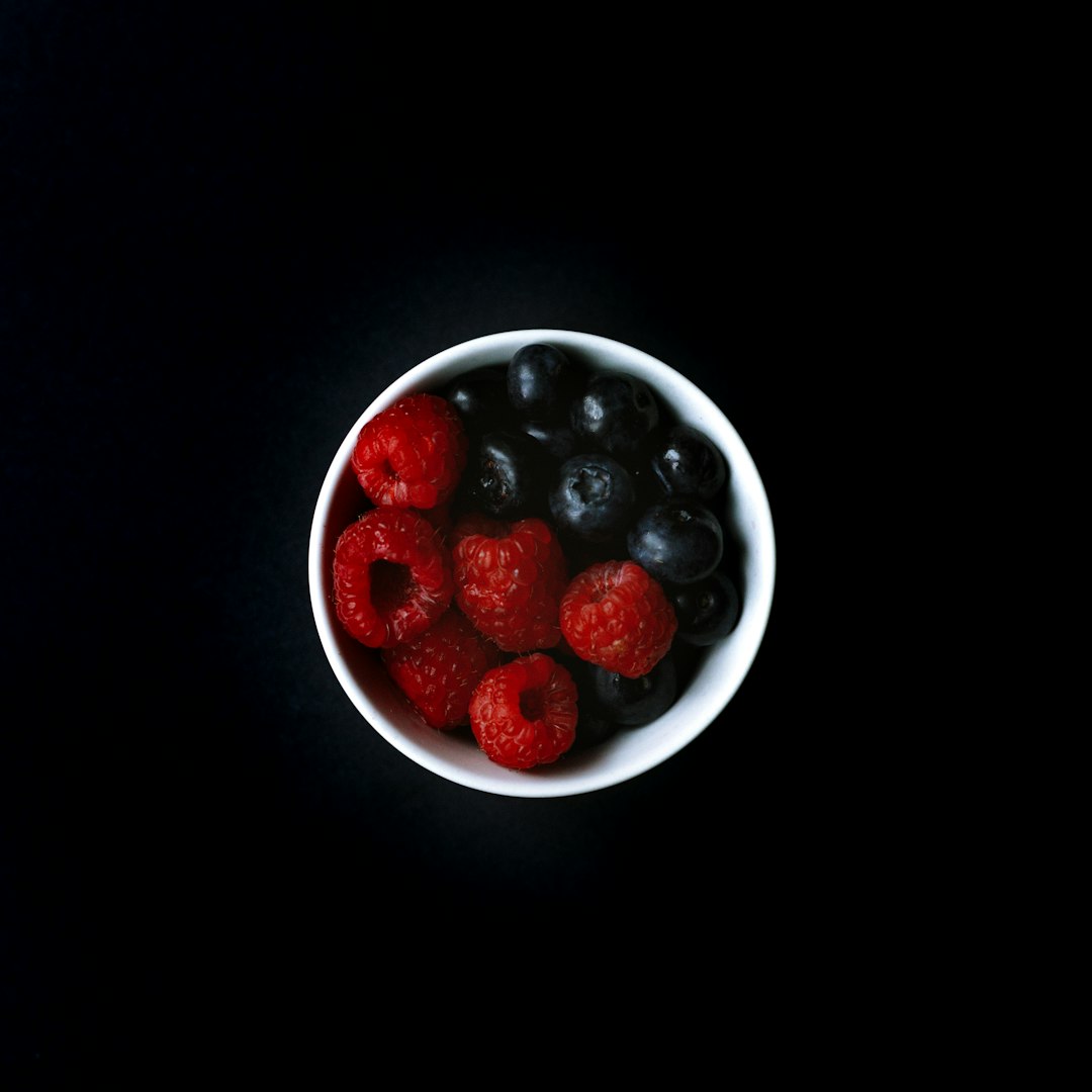 blueberry and raspberry on white ceramic bowl