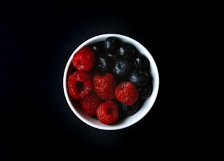 blueberry and raspberry on white ceramic bowl