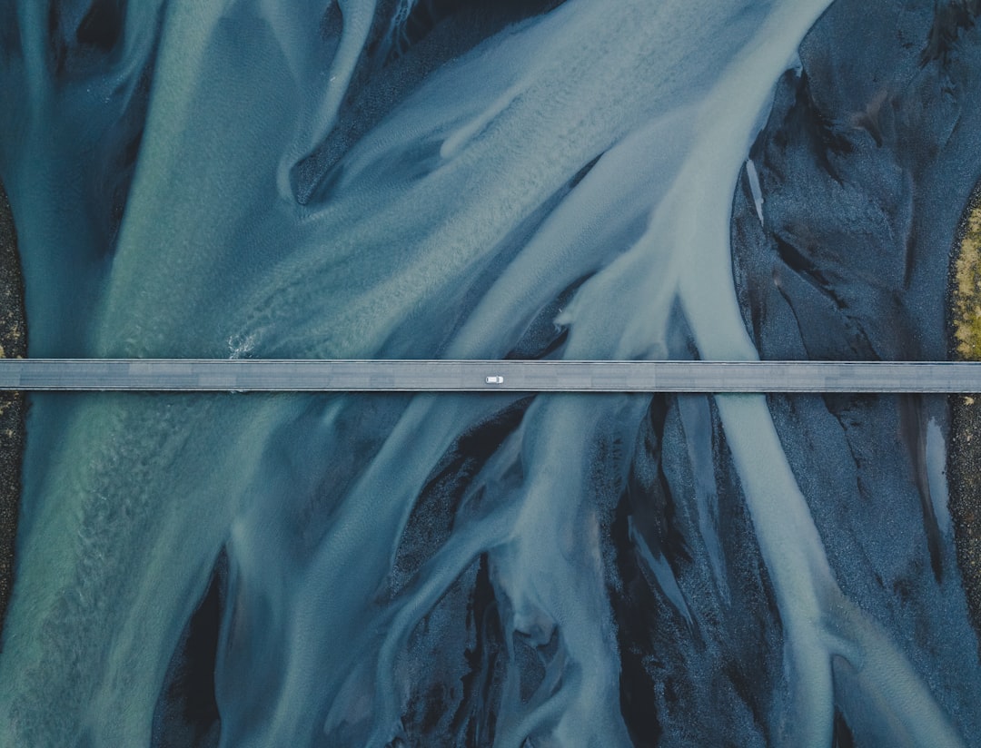 an aerial view of a road in the middle of a river, It’s often hard to see the beauty that’s right under your feet — or c