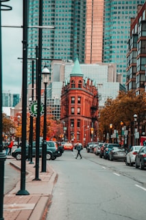 person crossing the road with parked cars beside the red building during daytime