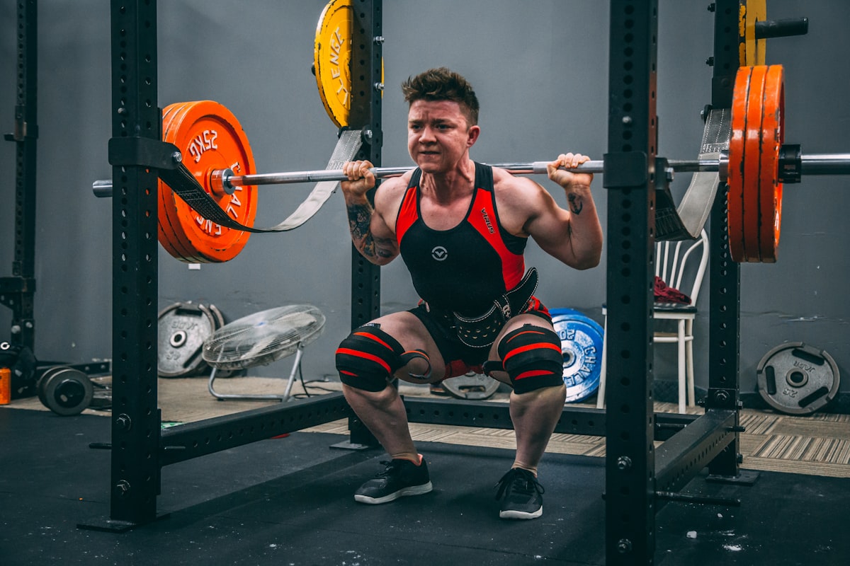 Lifter driving out of a heavy back squat in a power rack