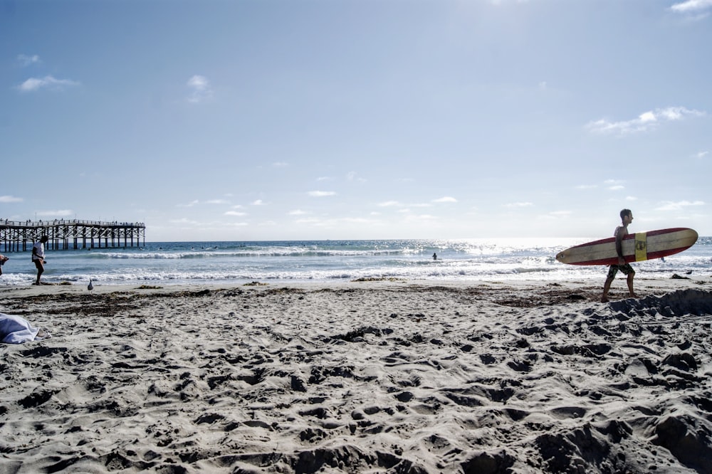 man carrying surfboard near shore during daytime