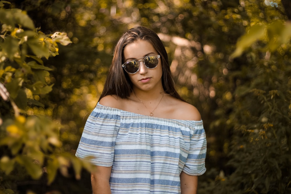 woman with sunglasses standing near trees during daytime