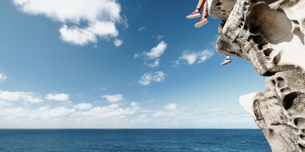 people sits on ledge overlooking sea