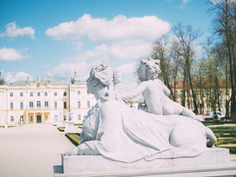 two person statue outdoor near the white building during daytime
