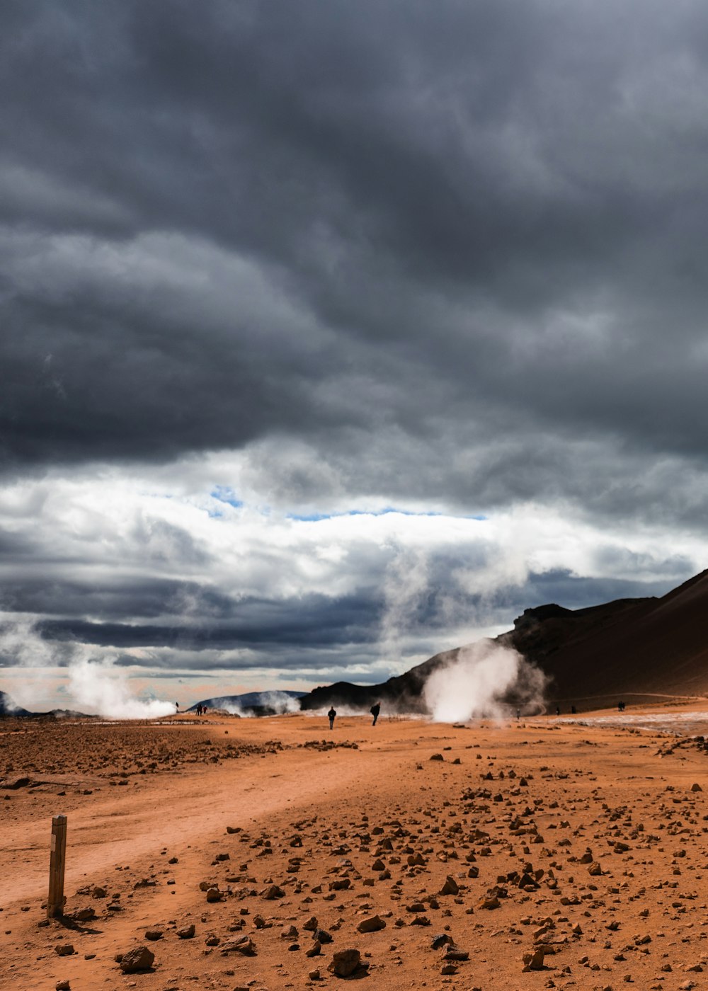 people on dirt covered field near the mountains