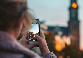 woman taking photo of a building during daytime