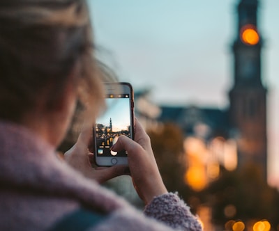 woman taking photo of a building during daytime