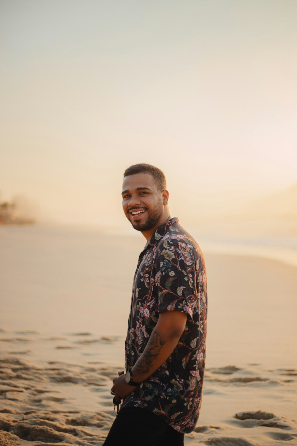 homem sorridente em pé na praia de areia durante o dia