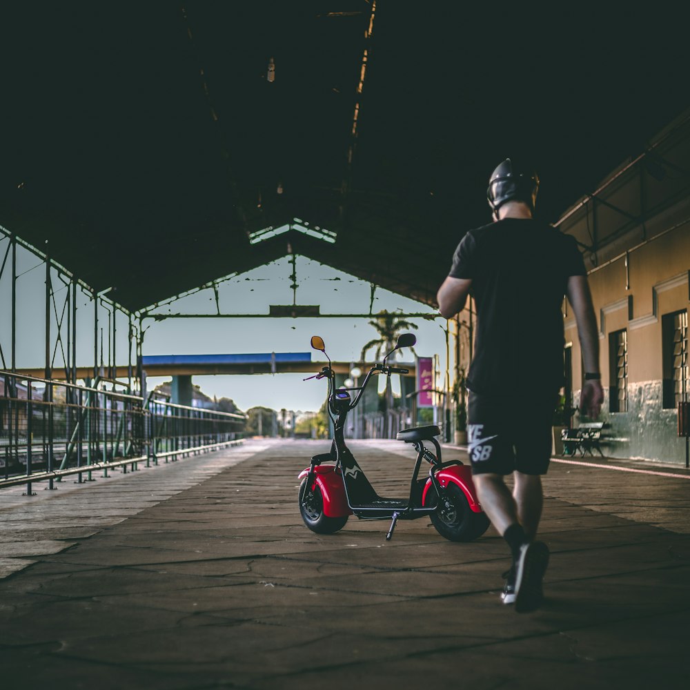 man walking near red motor scooter