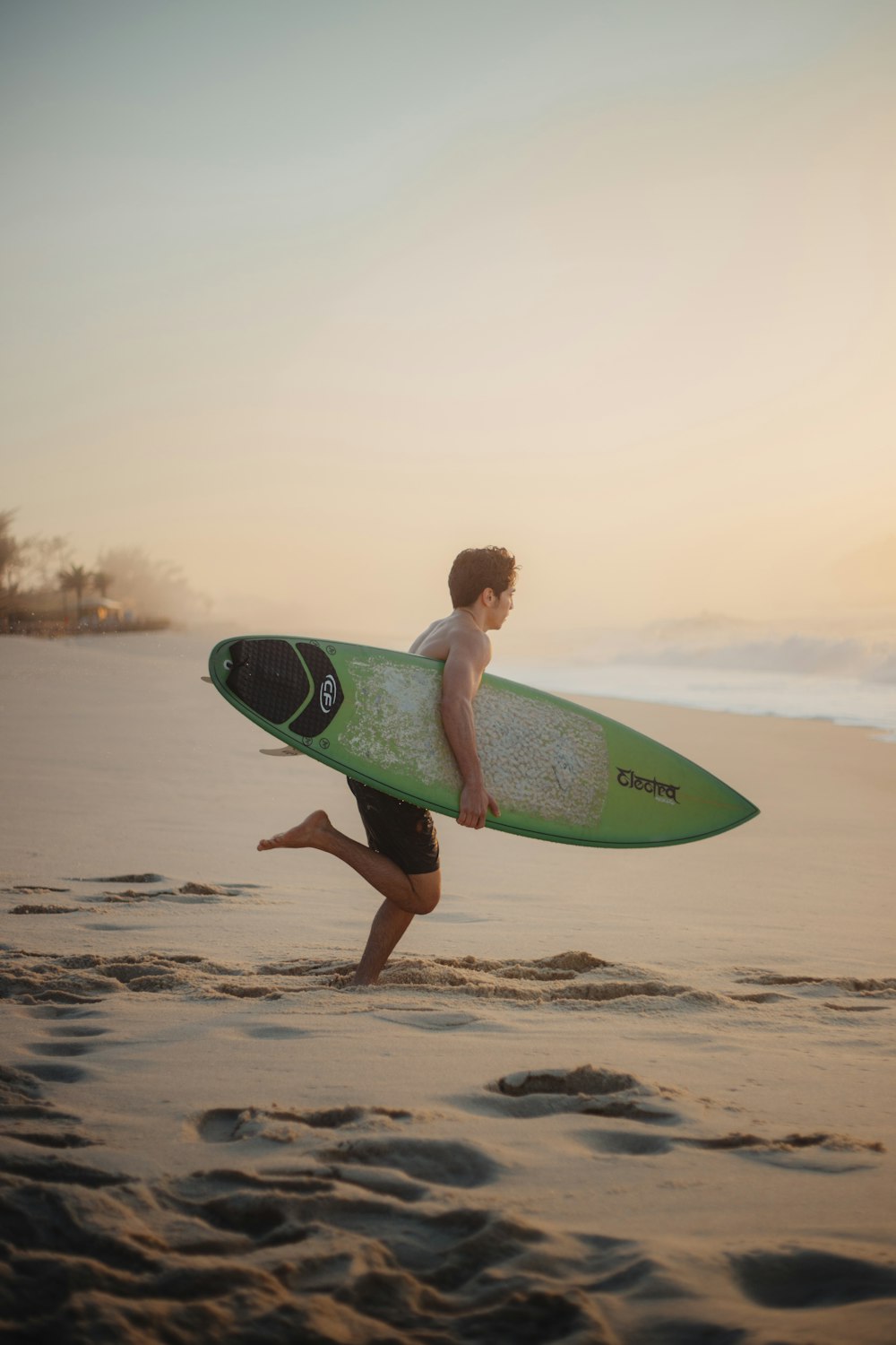 man run while carrying surfboard on beach