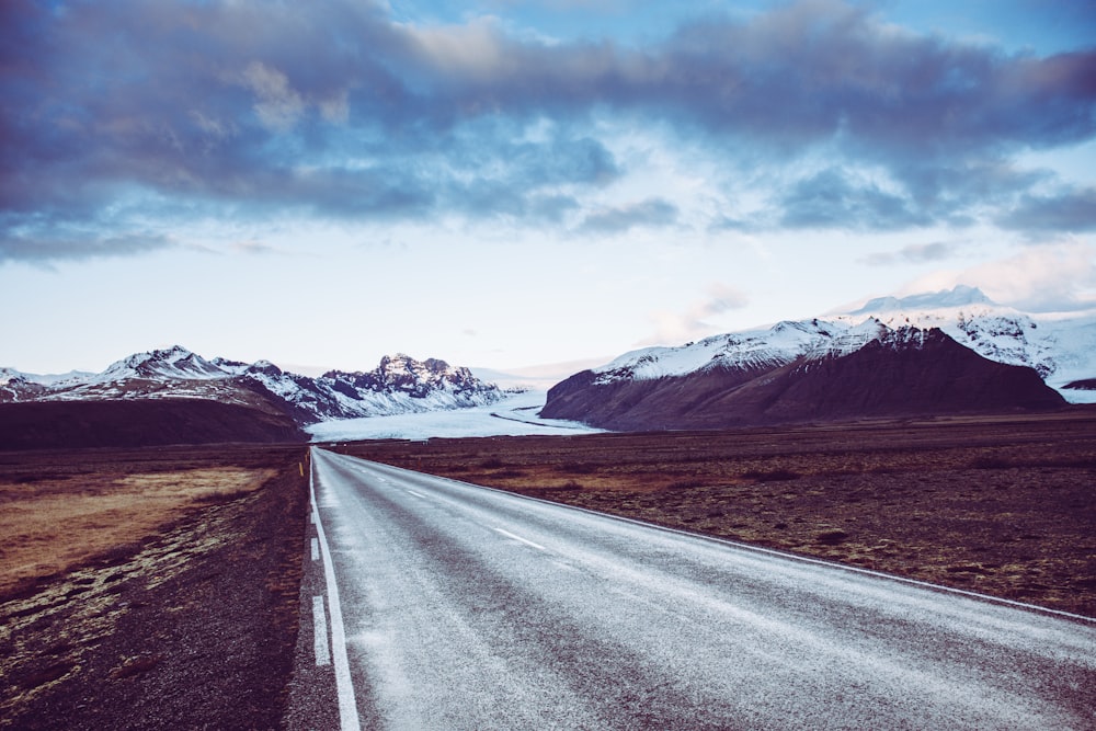 road and field and glacier field and mountains at the distance during day