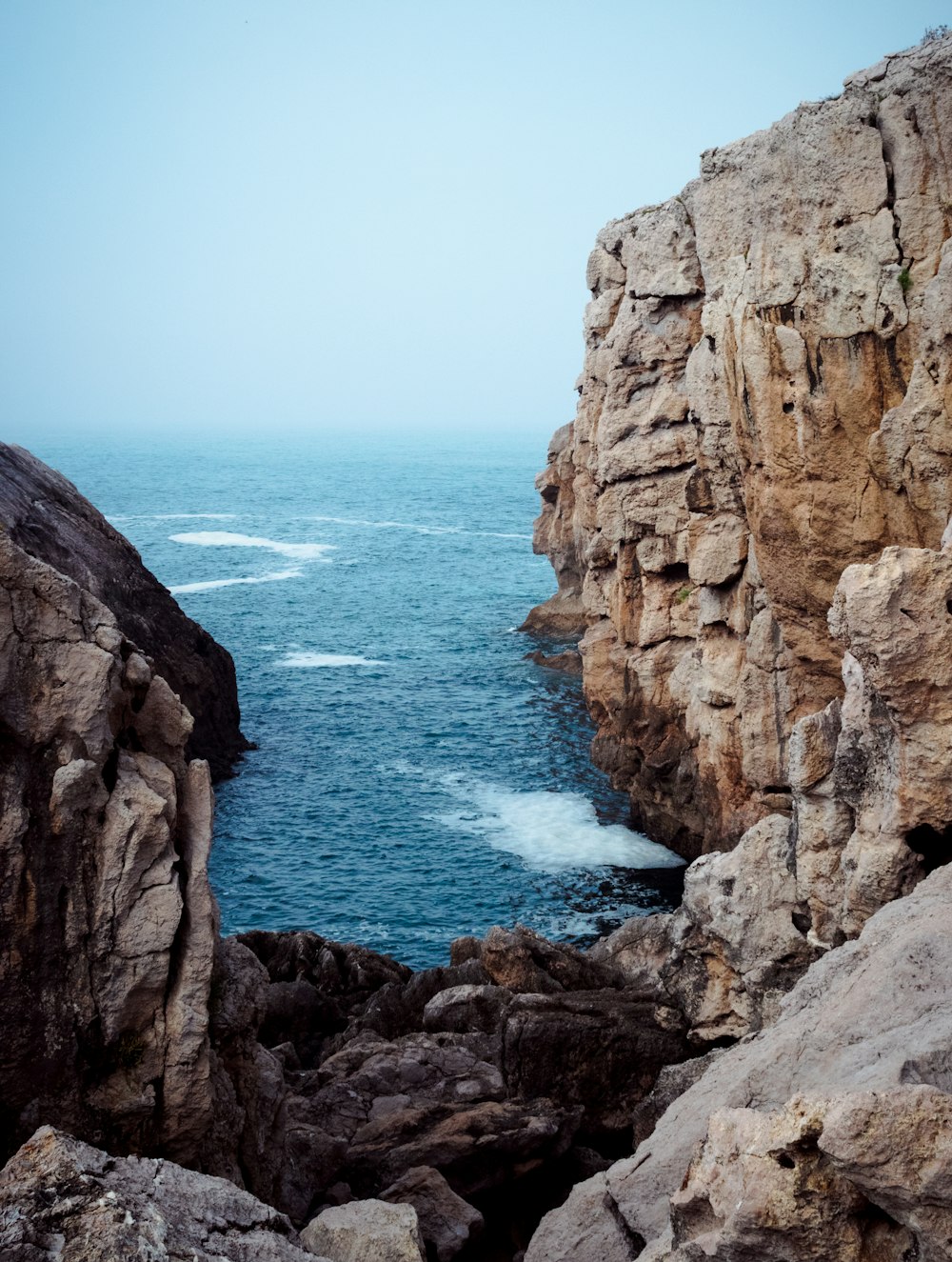 waving sea water heading to rock cliff