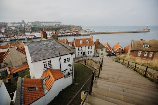houses near body of water during daytime in Whitby Abbey United Kingdom