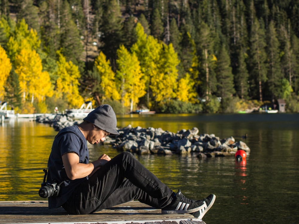 man sitting on dock with DSLR camera