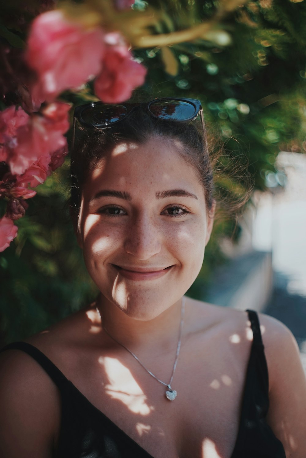 woman in black spaghetti strap top smiling beside bush