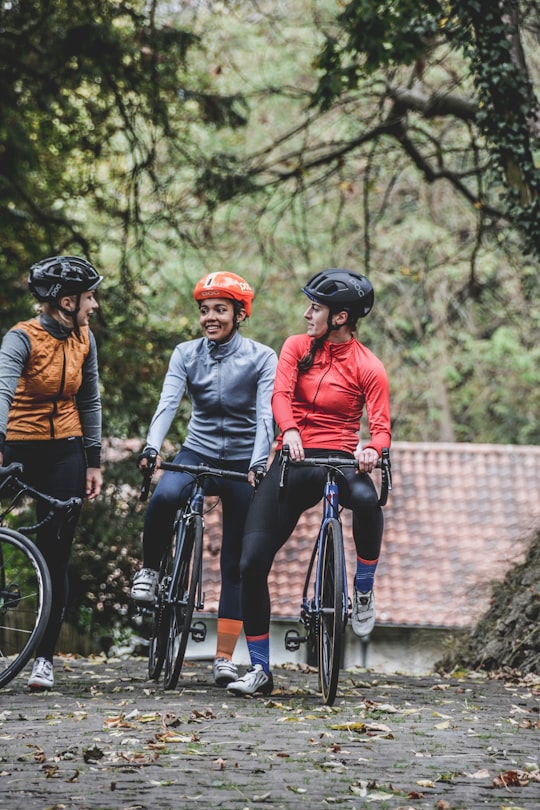 three people riding bike near trees during daytime in Muur van Geraardsbergen Belgium