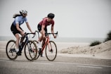 man and woman riding road bikes at the road near shore