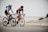 man and woman riding road bikes at the road near shore