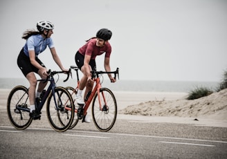 man and woman riding road bikes at the road near shore