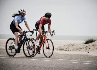 man and woman riding road bikes at the road near shore