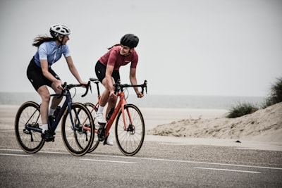 man and woman riding road bikes at the road near shore bike teams background