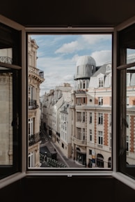 A focused student reviewing notes with a European cityscape visible through the window.