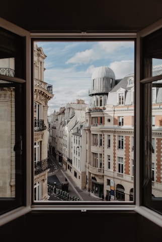A focused student reviewing notes with a European cityscape visible through the window.