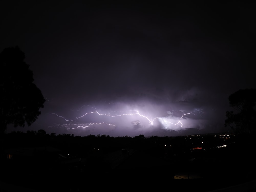 a lightning storm is seen over a city at night