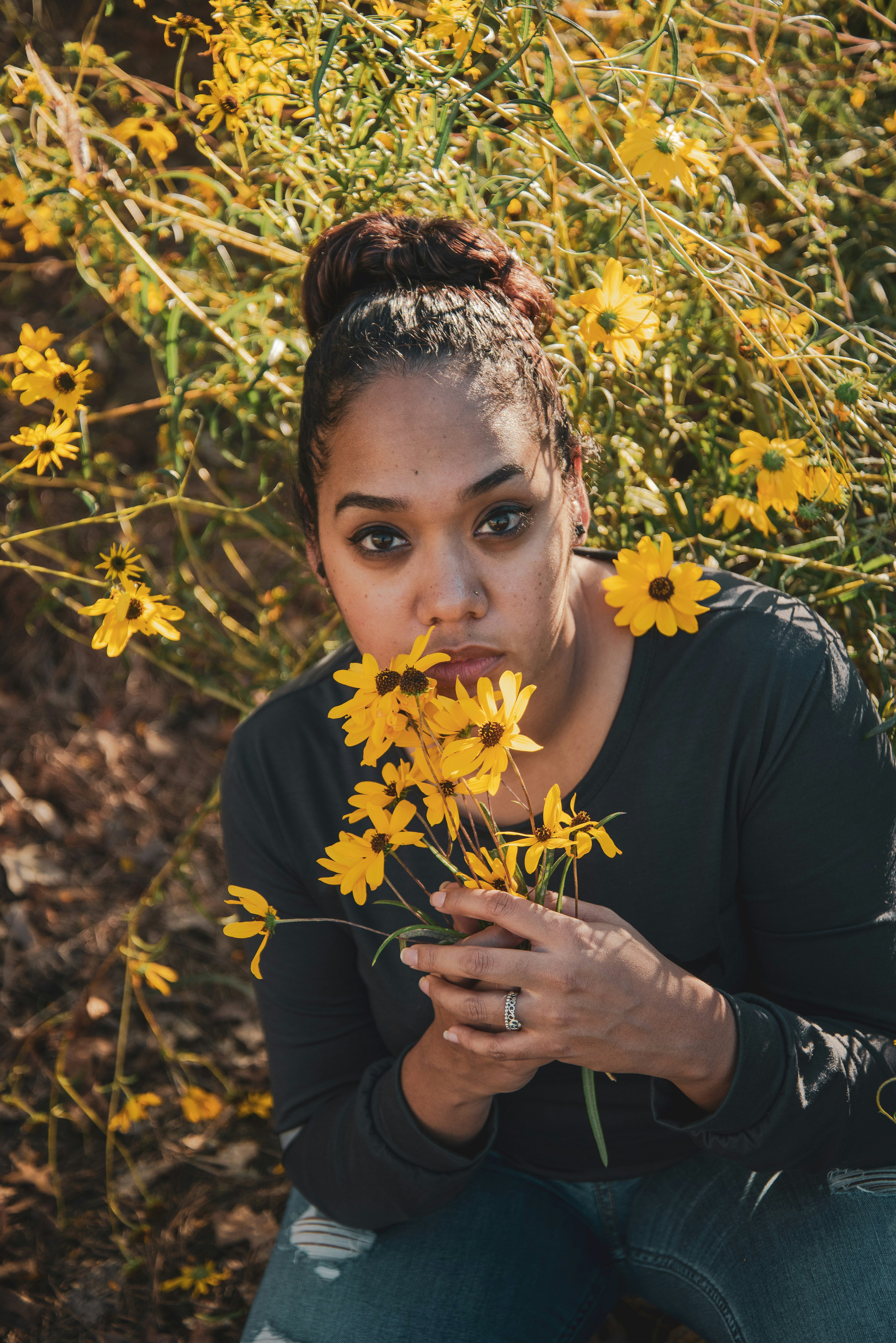 woman in black shirt holding yellow flowers