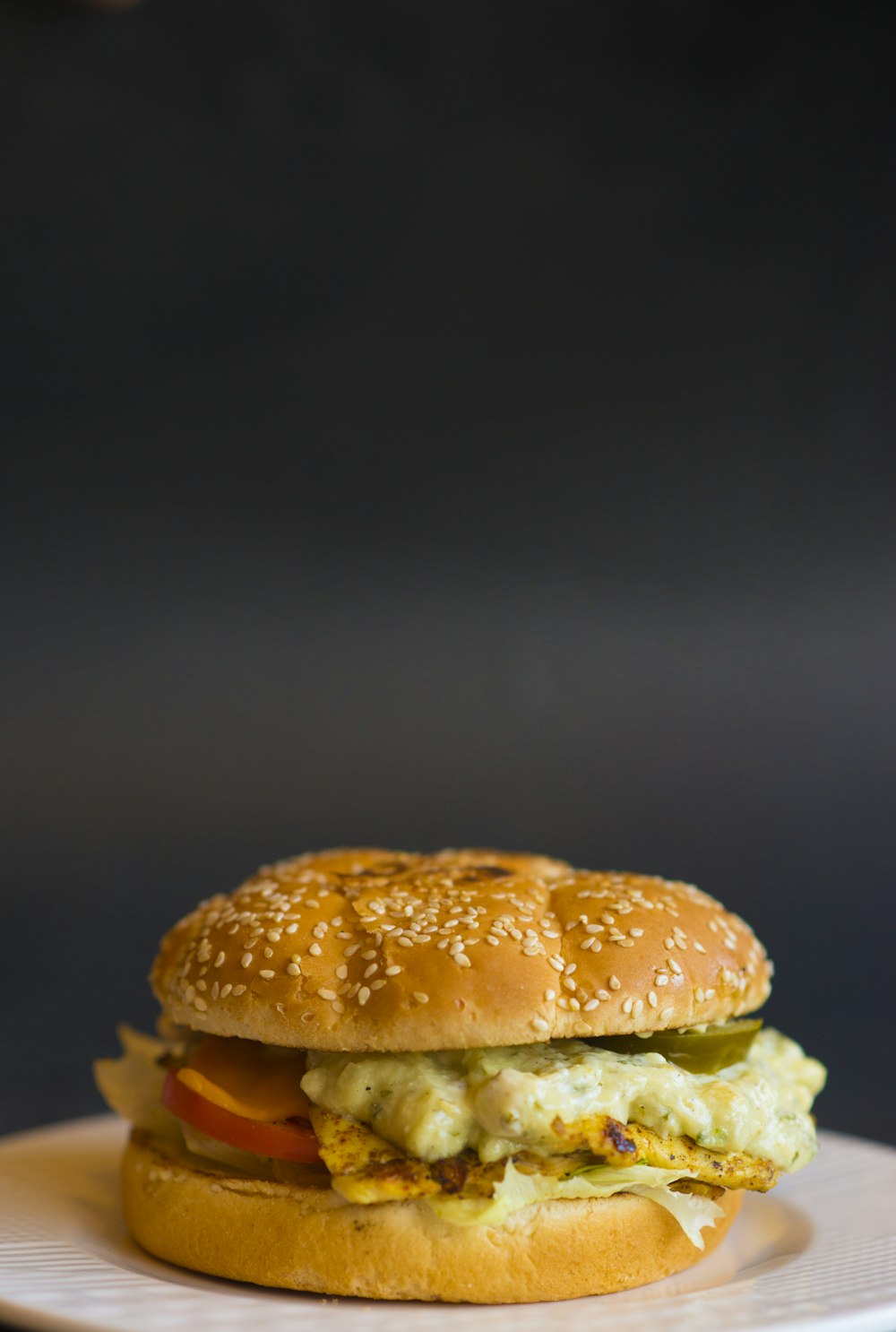 Burger mit Ei und Tomaten auf weißem Keramikteller