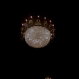 Luxurious crystal chandelier softly glowing in a warm white room ambiance.