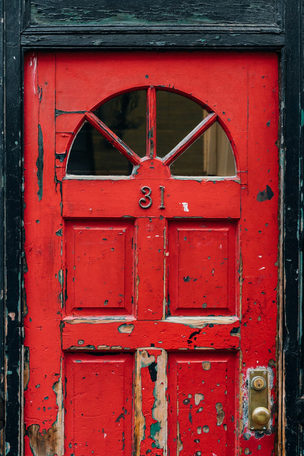 red wooden door with brass doorknob